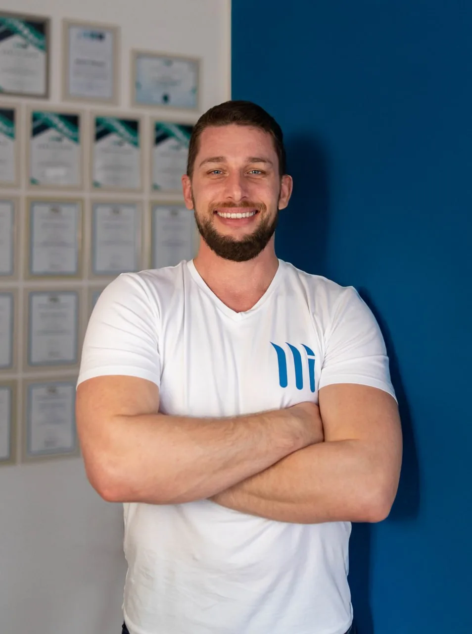 Marko Šimunek, fizioterapeut, u bijeloj MMASSAGE majici ispred zida s certifikatima